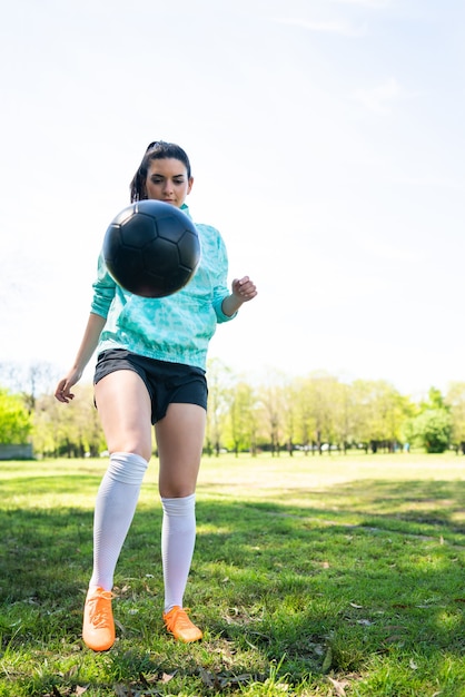 サッカーのスキルを練習し サッカーボールでトリックを行う若い女性の肖像画 ボールをジャグリングするサッカー選手 スポーツの概念 プレミアム写真