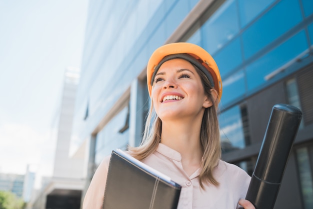 Portrait of professional architect woman wearing yellow helmet and standing outdoors. engineer and architect concept. Free Photo