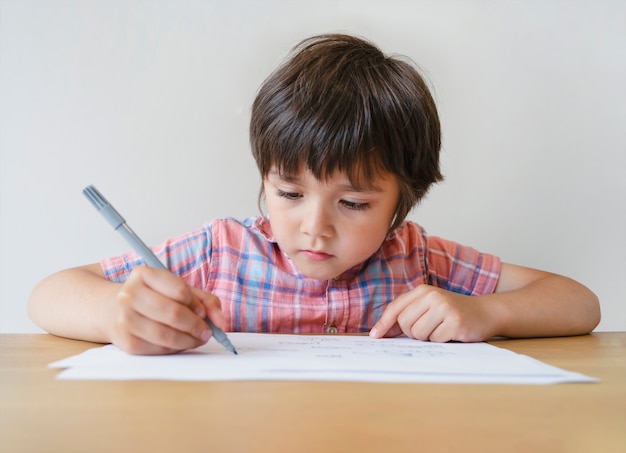 Premium Photo | Portrait of school kid boy sitting alone doing homework