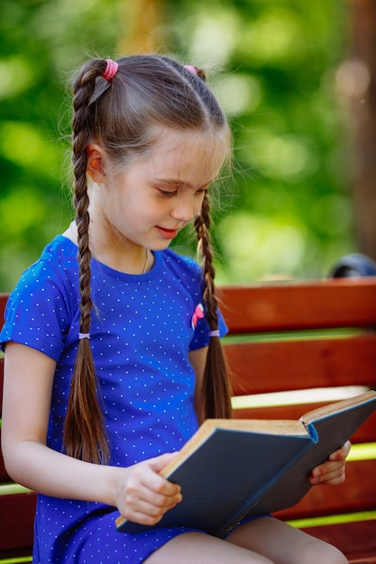 Premium Photo | Portrait of schoolgirl on a bench reading book ...