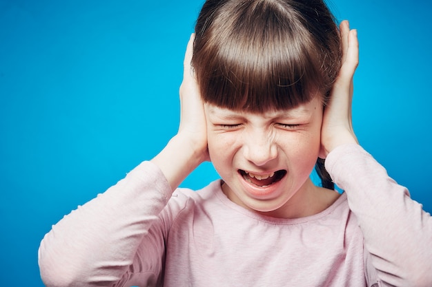 Portrait of a screaming girl with tightly shut eyes. child covering ears with hands Premium Photo