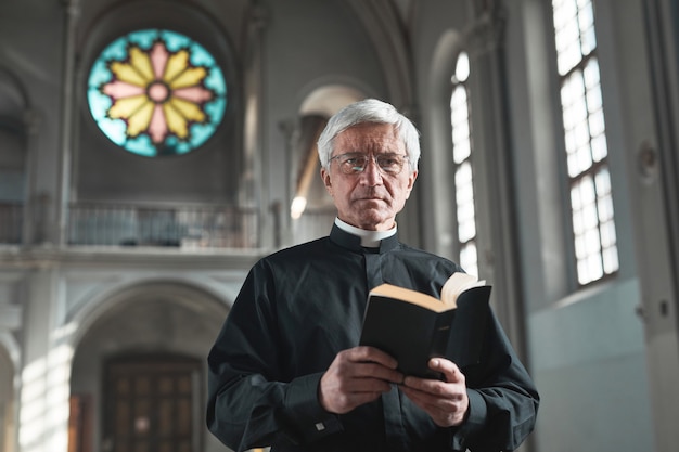 Premium Photo Portrait Of Senior Priest Holding The Bible And Looking At Camera While Standing