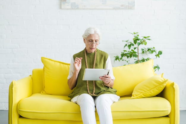 Free Photo | Portrait Of Senior Woman Sitting On Yellow Sofa Looking At ...