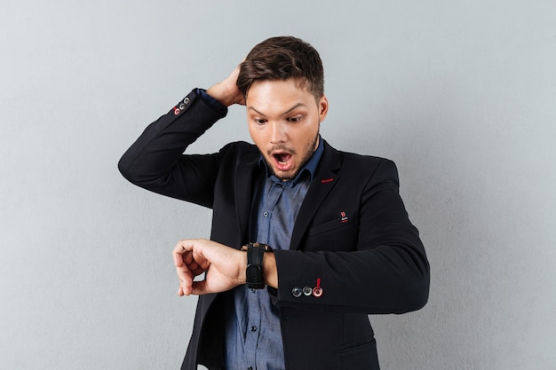 Portrait of a shocked businessman looking at wristwatch Free Photo