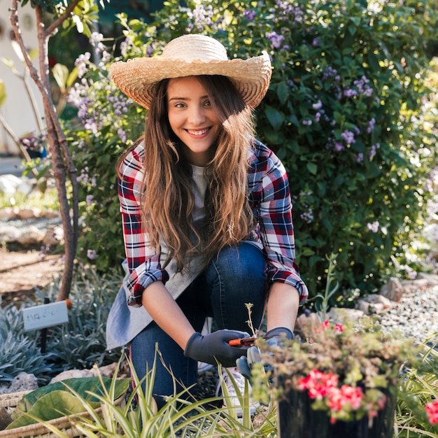 Free Photo | Portrait of a smiling female gardener wearing hat cutting ...