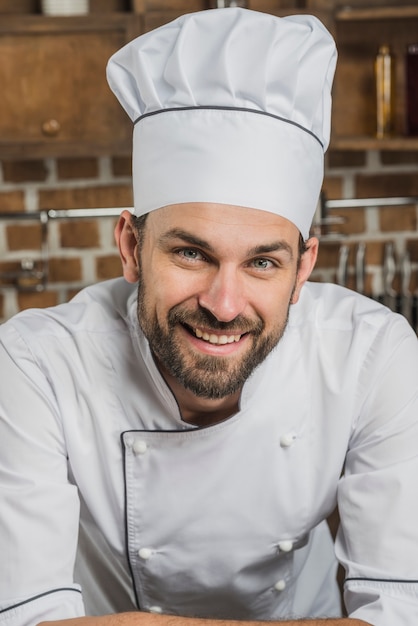 Free Photo Portrait of smiling male cook wearing chef's hat.