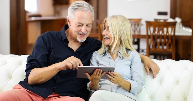 Happy Mature Couple Using Digital Tablet In Bed
