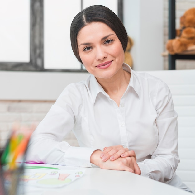 Portrait of smiling professional female psychologist sitting in her ...