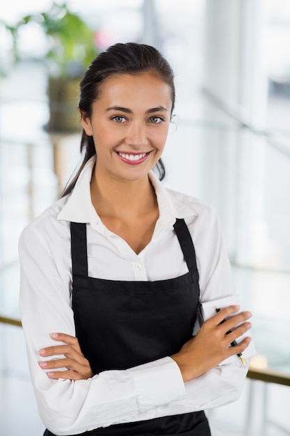 Premium Photo | Portrait of smiling waitress standing with arms crossed