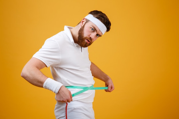 Portrait of a sports man measuring his waist with tape Free Photo