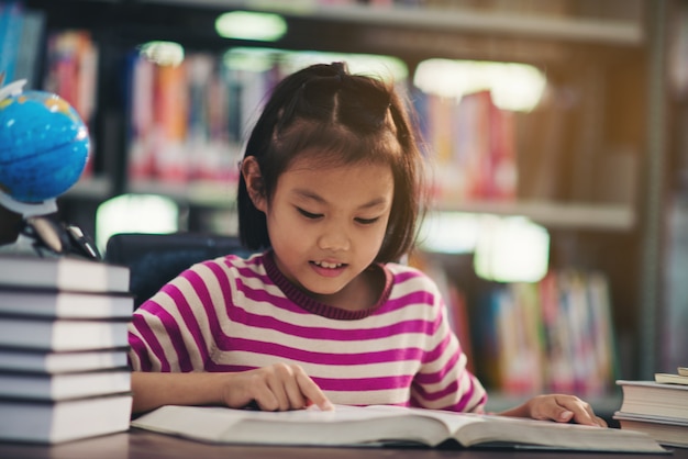 Portrait of a student child girl studying at library