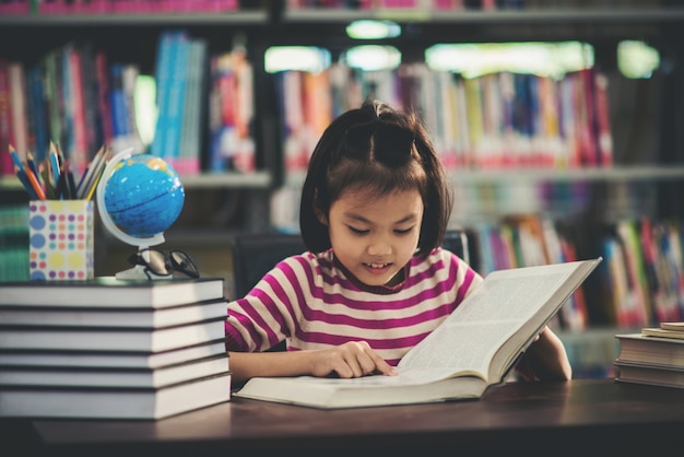 Portrait of a student child girl studying at library Free Photo