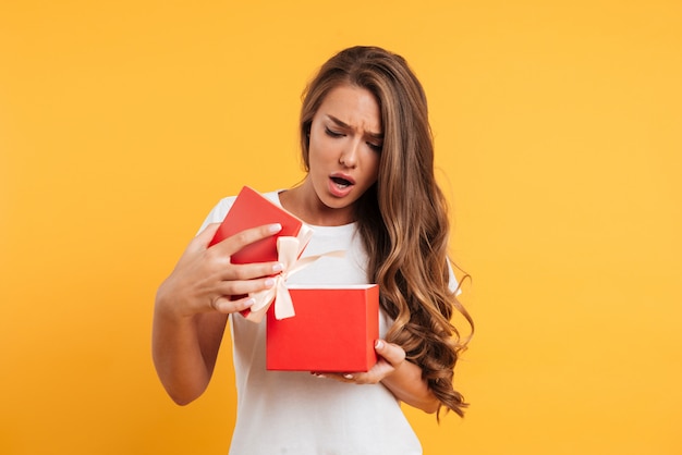 Free Photo | Portrait of an upset disappointed girl opening gift box