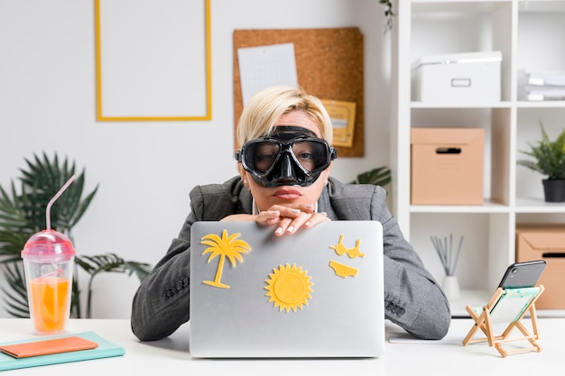 Portrait of woman in office prepared for summer holiday Free Photo