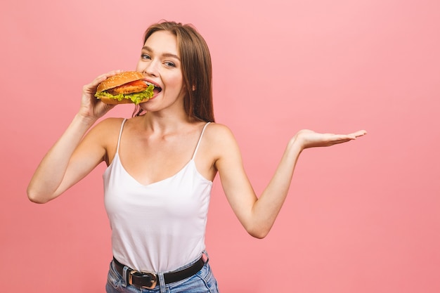 Premium Photo | Portrait of young beautiful hungry woman eating burger