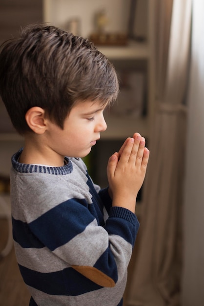 Portrait of young boy praying | Free Photo