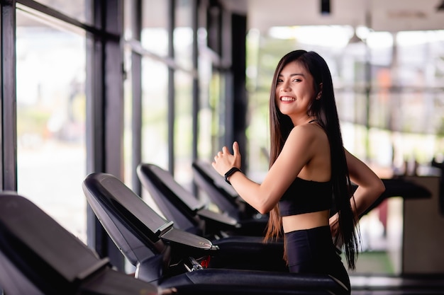 Portrait of young healthy woman running on treadmill, she smile during workout in gym, healthy lifestyle concept, copy space vertical image Free Photo