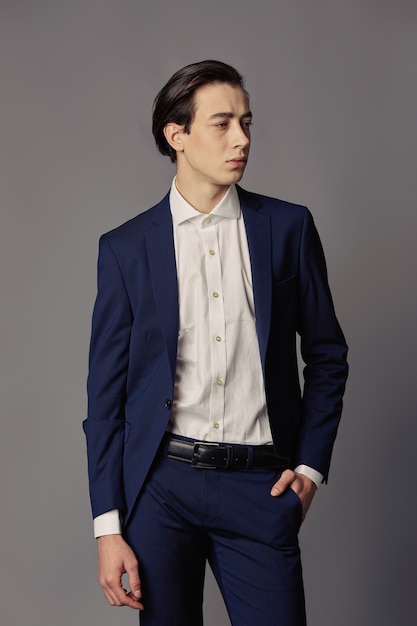 Premium Photo | Portrait young man in navy suit over gray wall