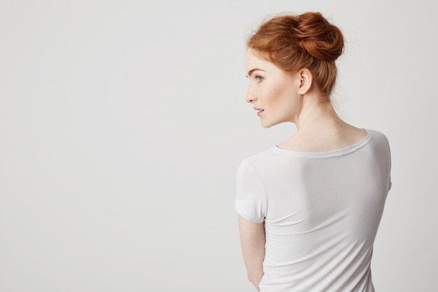 Portrait of young redhead girl with buns standing back to camera looking in side . Free Photo