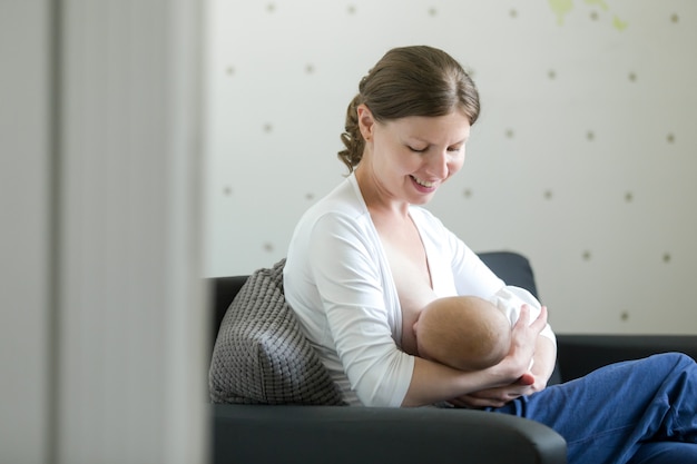 Portrait of a young woman breastfeeding a child on her knees Free Photo