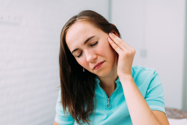 Premium Photo | Portrait of a young woman experiencing pain in the auricle.