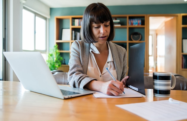 Portrait of young woman working from home with laptop and files. home office concept. new normal lifestyle. Free Photo