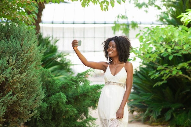 Positive black woman taking selfie photo in park Free Photo