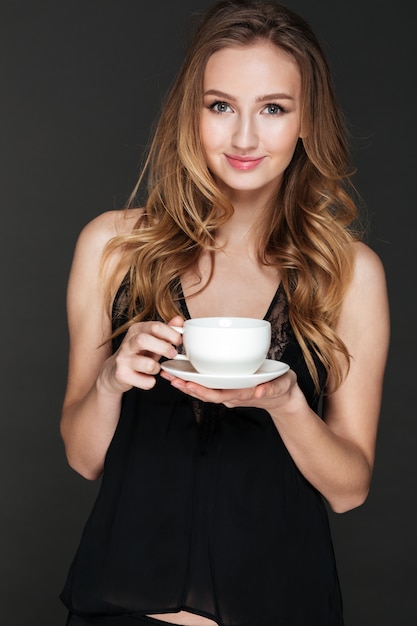 肯定的な女性がコーヒーを飲みながらポーズ 無料の写真