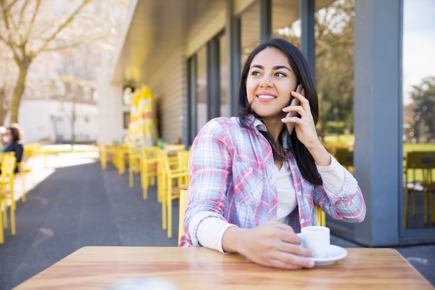 Positive woman talking on phone and drinking coffee Free Photo