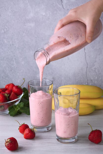 Download Premium Photo Pour Freshly Prepared Banana Strawberry Smoothie From A Bottle Into Glasses