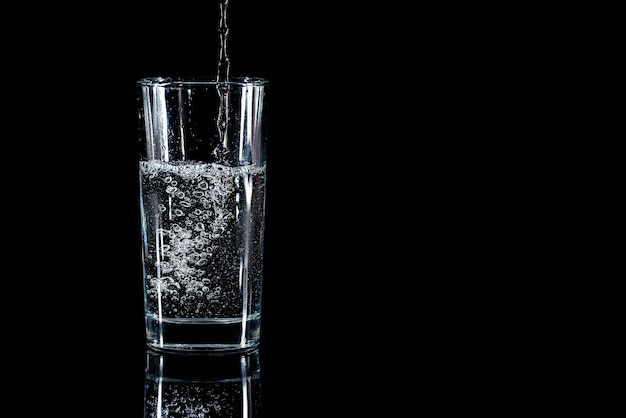 Premium Photo | Pouring water into glass on black