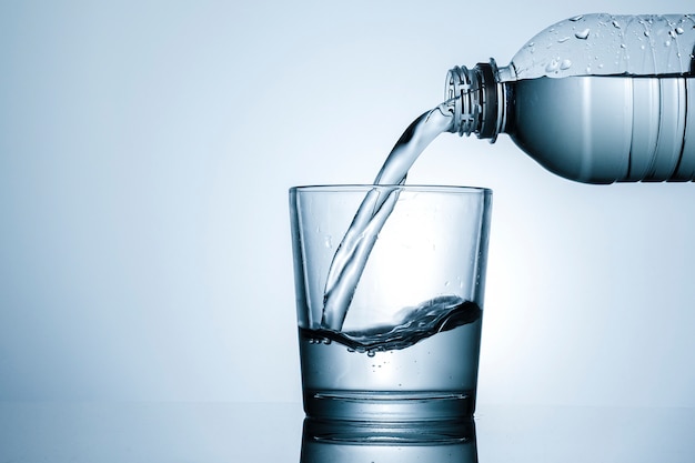 Premium Photo | Pouring water into a tumbler in close up