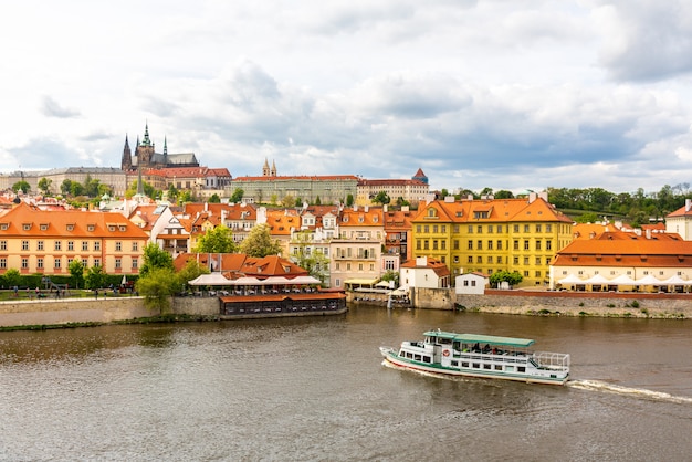 川 チェコ共和国の遊覧船でプラハの街並み 旅行や観光で有名な古代建築物があるヨーロッパの町 プレミアム写真
