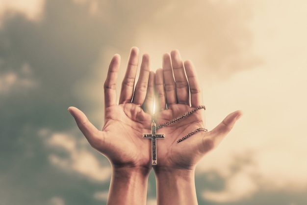 祈りの手は 宗教と神への信仰を信じて十字架または金属製の十字架を握る プレミアム写真