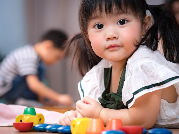2歳の健康的な愛らしいアジアの女の子の貴重な顔は 床に横になって カラフルな木製モンテッソーリ感覚おもちゃを遊んでいます かわいい幼児少女 最愛の娘 子どもの発達 プレミアム写真