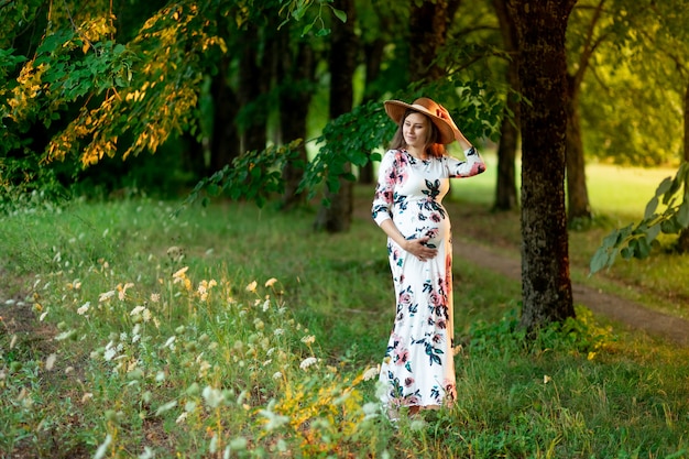 Premium Photo A Pregnant Woman In A Dress And Hat Walks In The Forest