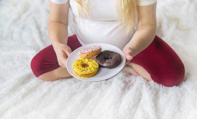 A Pregnant Woman Eats Sweet Donuts Selective Focus Premium Photo