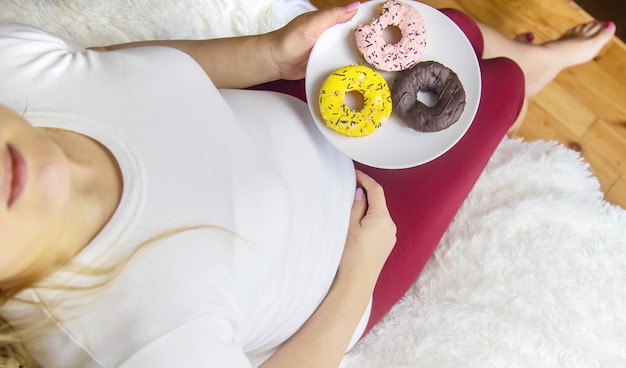 A pregnant woman eats sweet donuts. selective focus ...