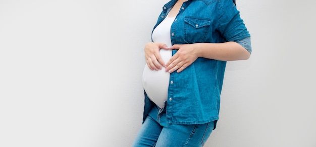 Premium Photo | Pregnant Woman Holds Hands On Belly On A Grey ...