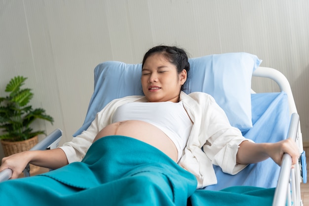 The pregnant woman is suffering because close to the birth, lying in a patient bed Premium Photo
