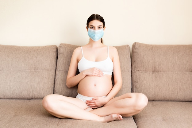 Premium Photo | Pregnant woman is wearing protective medical mask to  protect herself and future baby from coronavirus. mother is sitting on the  couch at home. global quarantine concept