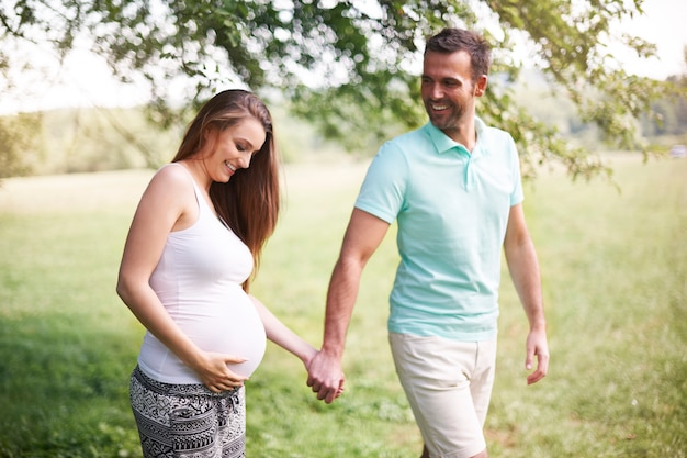 Pregnant woman with husband walking on meadow Free Photo