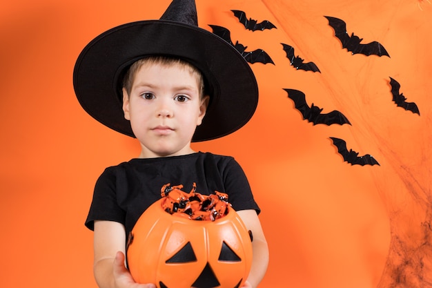 Premium Photo | A preschool boy in a witch costume holds a pumpkin with ...