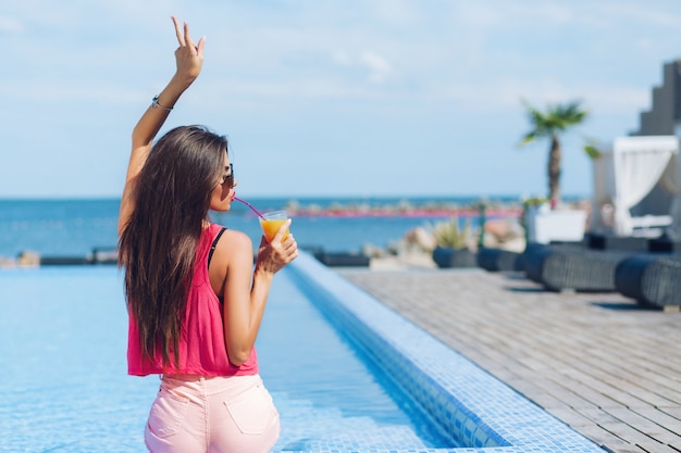 Free Photo | Pretty brunette girl with long hair is sitting near pool ...