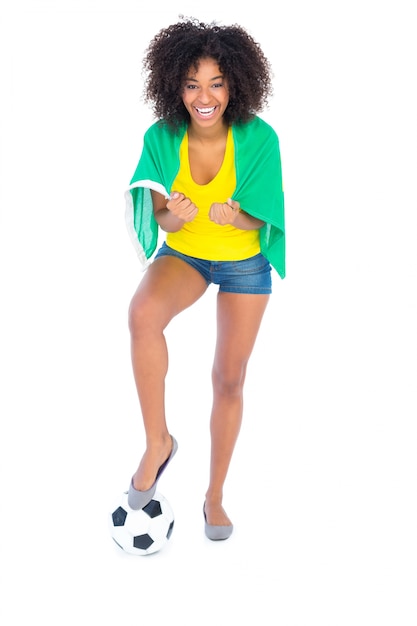Pretty football fan holding brazilian flag cheering at camera Premium Photo