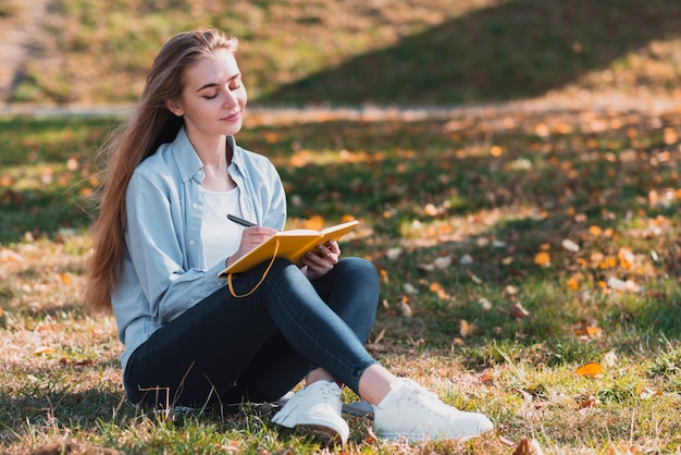 Pretty girl sitting in nature and writing Photo | Free Download