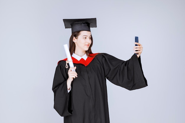 Free Photo | Pretty graduate student in gown taking selfie. high ...