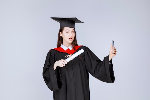 Free Photo | Pretty graduate student in gown taking selfie. high ...