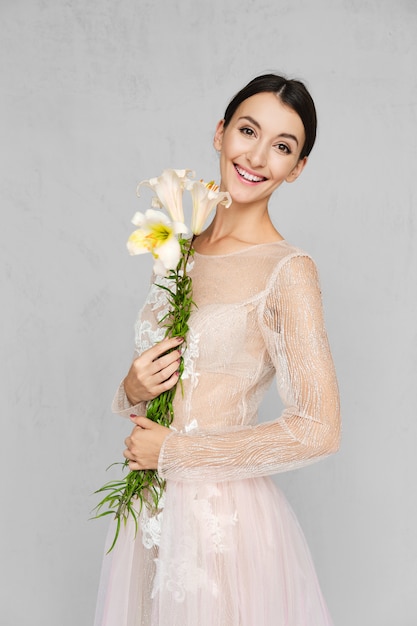 手に花を持つポーズのレースと淡い透明なドレスのきれいな女性 プレミアム写真