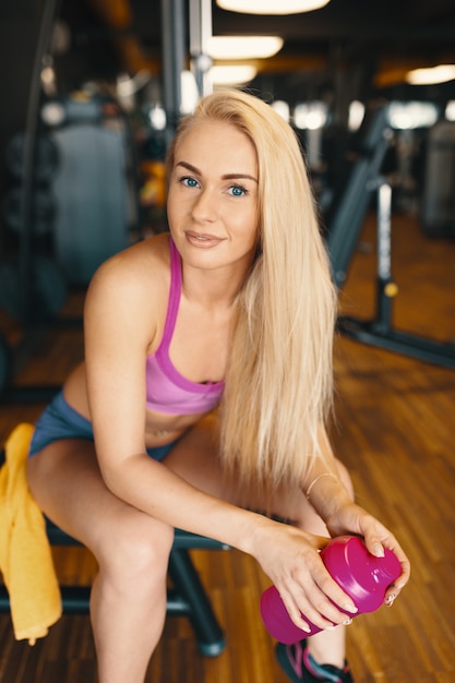 Pretty Woman With Long Blond Hair Relaxing In The Gym With A Pink
